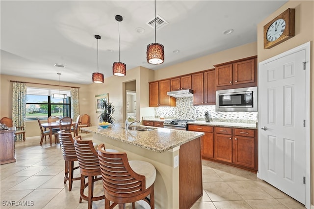 kitchen featuring sink, hanging light fixtures, a kitchen breakfast bar, an island with sink, and appliances with stainless steel finishes