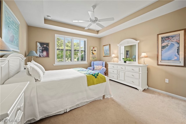 bedroom with light carpet, a raised ceiling, and ceiling fan