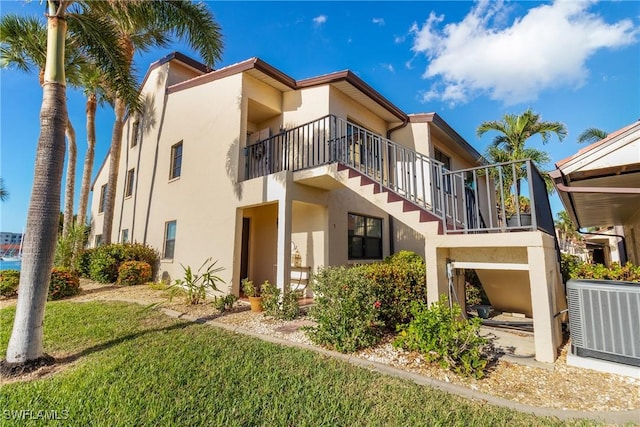 exterior space with a balcony, cooling unit, and a lawn