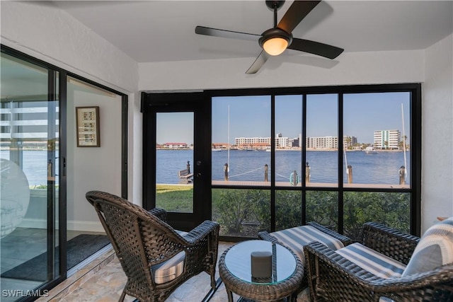 sunroom featuring a water view and ceiling fan