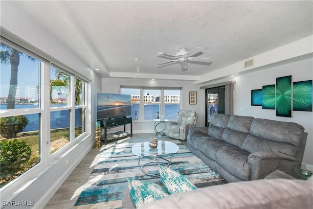 living room with ceiling fan, a textured ceiling, and wood-type flooring