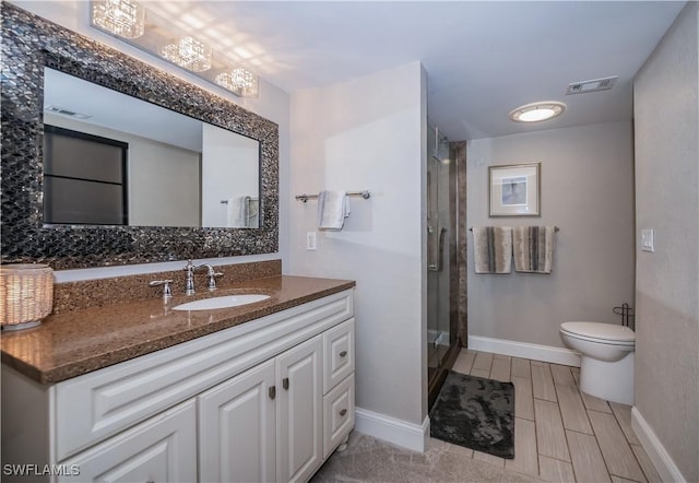 bathroom featuring a shower with shower door, toilet, and vanity