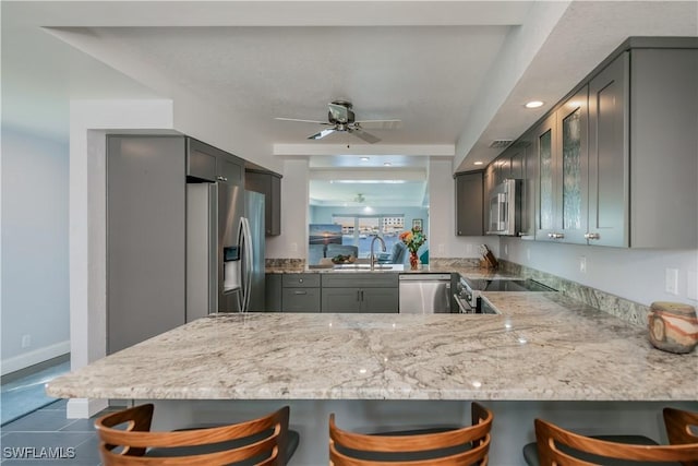 kitchen featuring a breakfast bar area, stainless steel appliances, kitchen peninsula, and ceiling fan