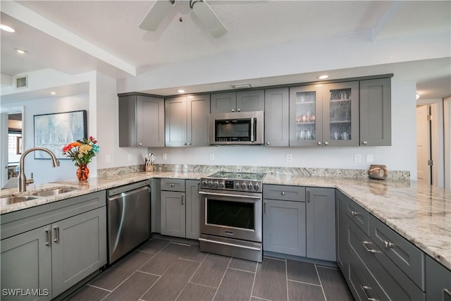 kitchen featuring kitchen peninsula, sink, light stone countertops, gray cabinetry, and stainless steel appliances