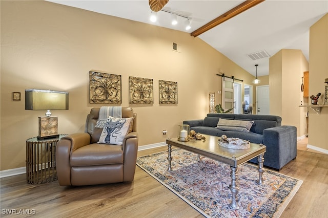 living room with beam ceiling, a barn door, light hardwood / wood-style flooring, high vaulted ceiling, and track lighting