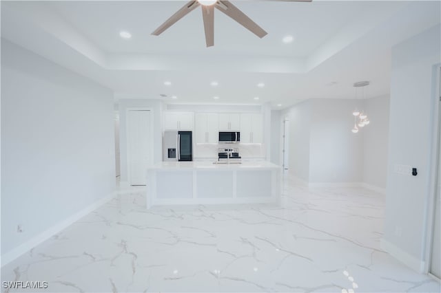 unfurnished living room with ceiling fan and a tray ceiling