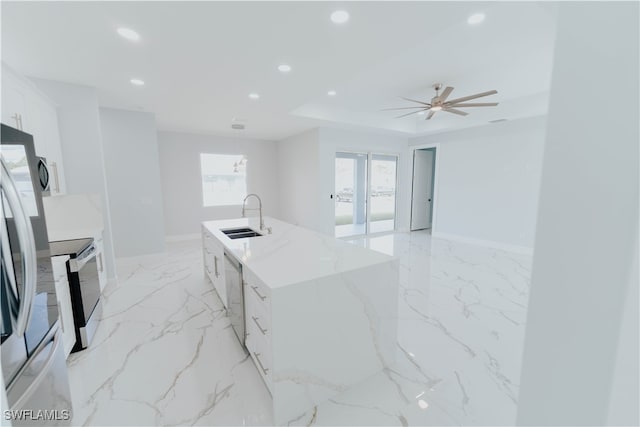 kitchen featuring stainless steel appliances, ceiling fan, sink, a center island with sink, and white cabinets