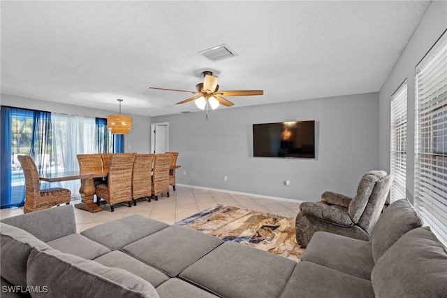 tiled living room featuring ceiling fan, a healthy amount of sunlight, and a textured ceiling