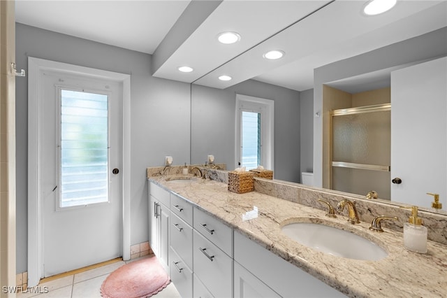 bathroom with tile patterned flooring, vanity, a shower with shower door, and toilet