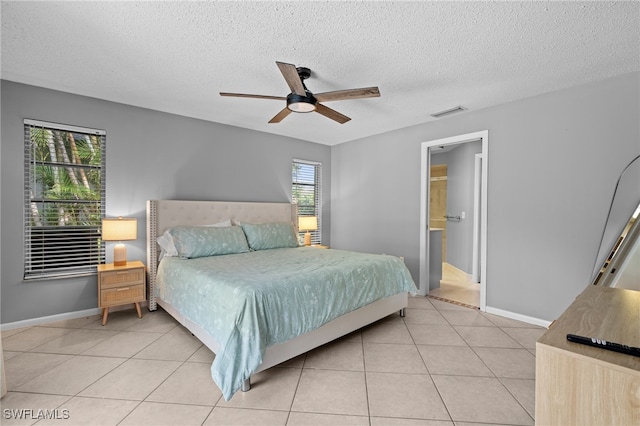 bedroom featuring ceiling fan, light tile patterned floors, and a textured ceiling