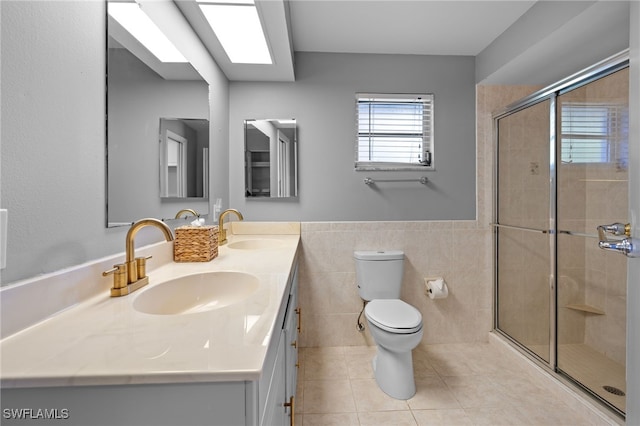 bathroom with tile patterned flooring, toilet, vanity, a shower with shower door, and tile walls