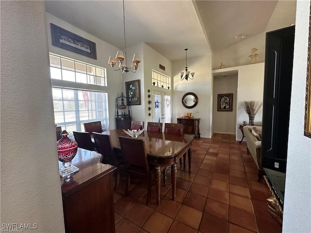 dining area featuring a notable chandelier, dark tile patterned floors, and high vaulted ceiling