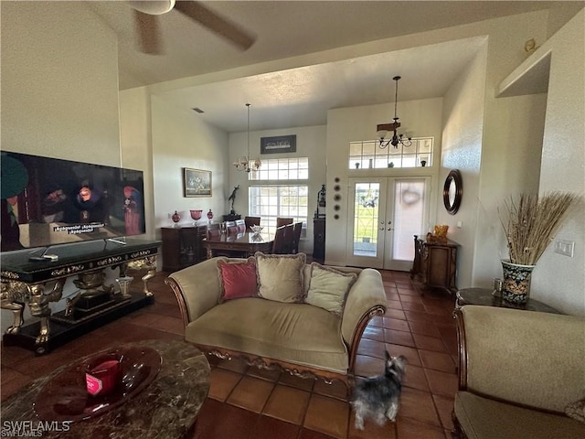 living room with dark tile patterned flooring, ceiling fan with notable chandelier, and french doors