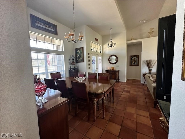 dining area with dark tile patterned flooring, a notable chandelier, and high vaulted ceiling