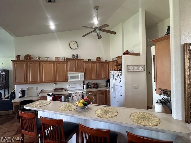 kitchen with kitchen peninsula, tile patterned floors, white appliances, ceiling fan, and lofted ceiling