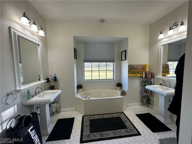 bathroom featuring a tub to relax in, a wealth of natural light, and double sink