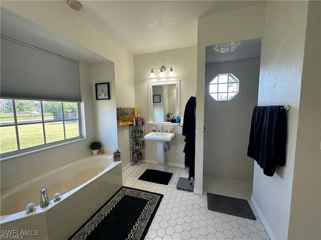 bathroom featuring a healthy amount of sunlight, a textured ceiling, and independent shower and bath