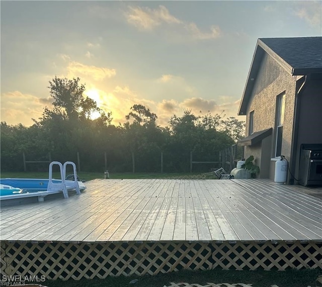 pool at dusk featuring a wooden deck