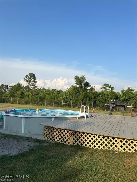 view of swimming pool with a deck and a lawn