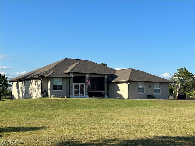 back of house featuring a lawn and a sunroom