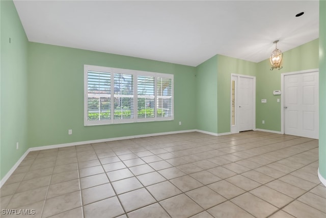 spare room with an inviting chandelier and light tile patterned flooring