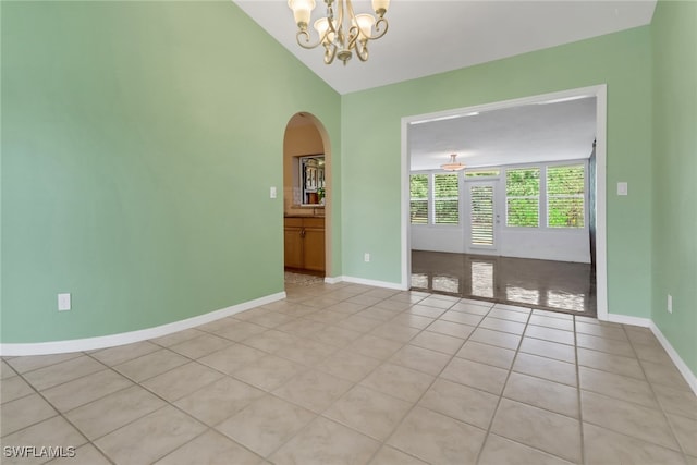 tiled empty room featuring a notable chandelier and lofted ceiling