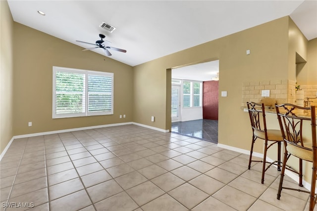 empty room with light tile patterned floors, a healthy amount of sunlight, and vaulted ceiling