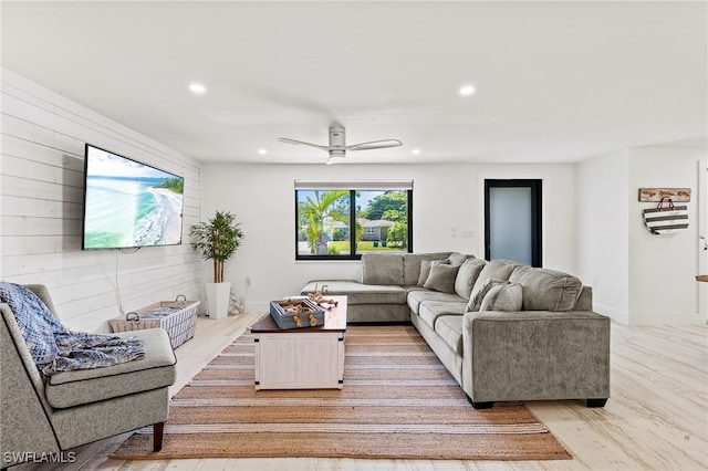 living area featuring recessed lighting, baseboards, wood walls, and light wood finished floors