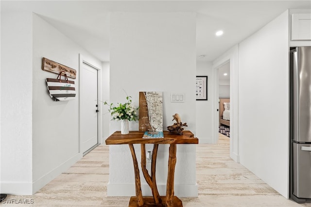 hall featuring recessed lighting, light wood-style flooring, and baseboards