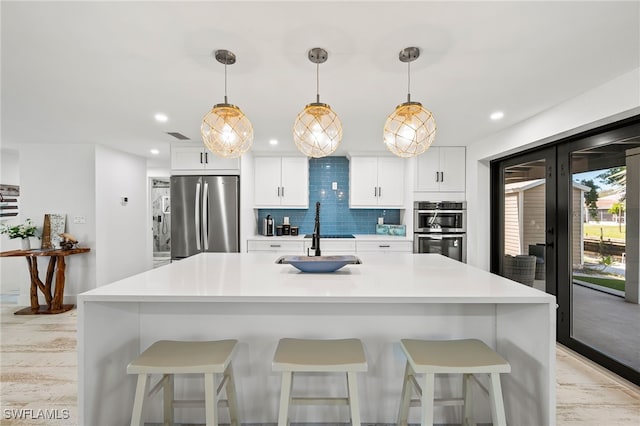 kitchen with french doors, backsplash, appliances with stainless steel finishes, white cabinetry, and a sink