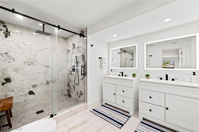 bathroom featuring recessed lighting, two vanities, a sink, and a marble finish shower