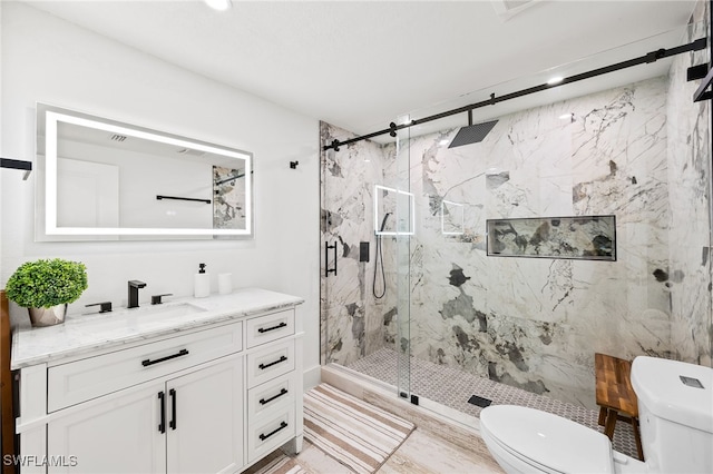 bathroom with vanity, a marble finish shower, and toilet