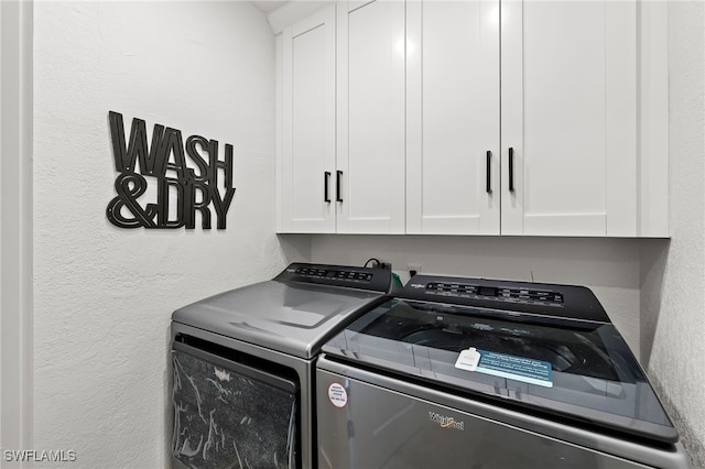 laundry room with a textured wall, separate washer and dryer, and cabinet space