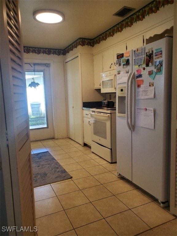 kitchen with light tile patterned floors, white cabinets, and white appliances