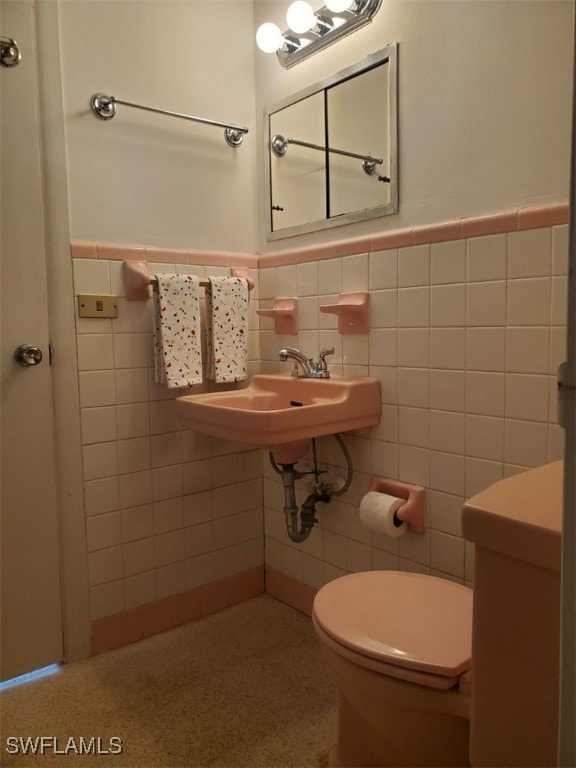 bathroom featuring sink, tile walls, and toilet