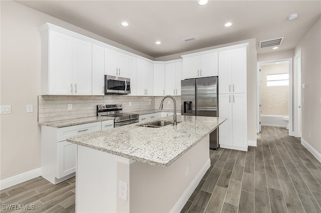 kitchen featuring a center island with sink, visible vents, appliances with stainless steel finishes, wood tiled floor, and a sink