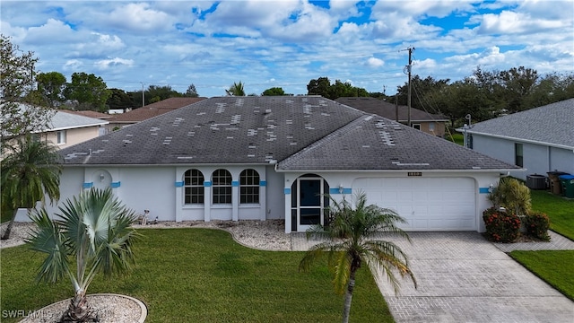 view of front of home featuring a front yard, central AC, and a garage