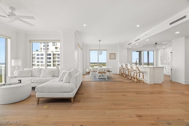 living room with light hardwood / wood-style flooring, plenty of natural light, and ornamental molding