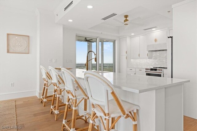 4951 Bonita Bay Blvd Unit 2205, Bonita Springs, FL 34134 - kitchen featuring a ceiling fan, high end stove, a breakfast bar, light stone counters, and white cabinets