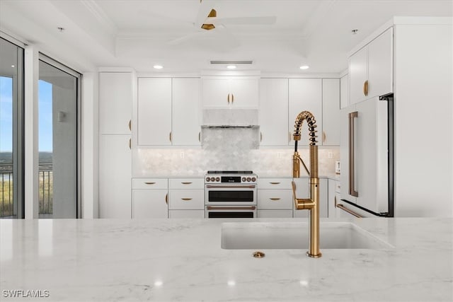 kitchen featuring crown molding, high end appliances, white cabinetry, and light stone counters