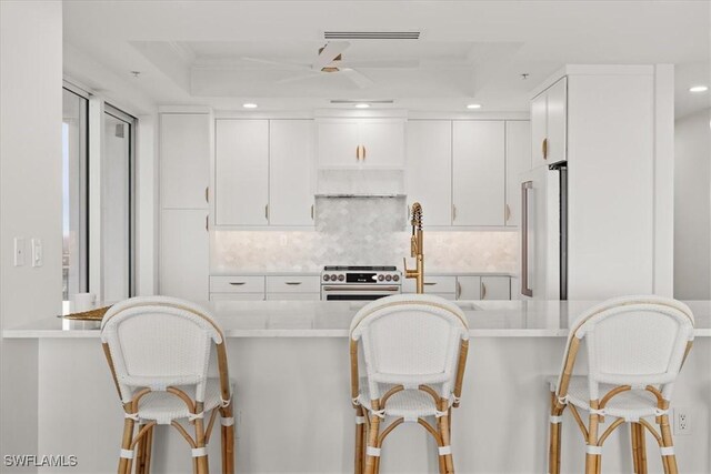 4951 Bonita Bay Blvd Unit 2205, Bonita Springs, FL 34134 - kitchen featuring premium appliances, a kitchen breakfast bar, decorative backsplash, recessed lighting, and white cabinetry