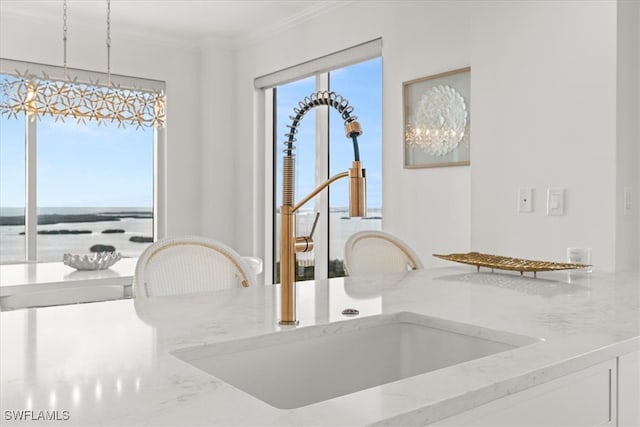 interior details featuring crown molding, sink, light stone countertops, and hanging light fixtures