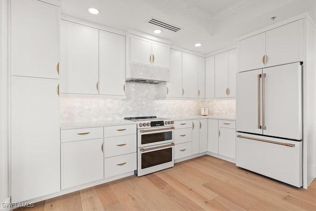 kitchen with backsplash, white cabinets, light hardwood / wood-style floors, and high end appliances