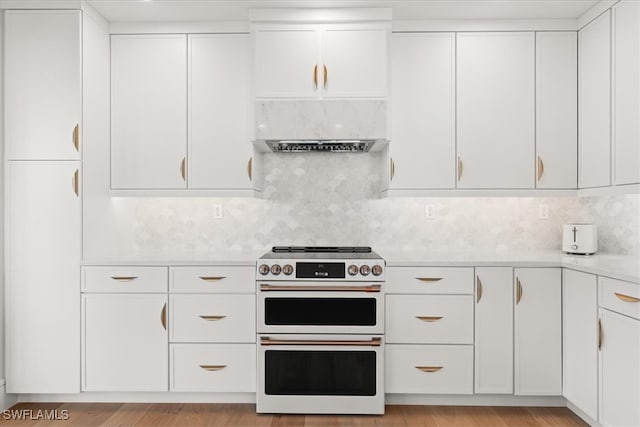 kitchen featuring decorative backsplash, white cabinets, double oven range, and light wood-type flooring