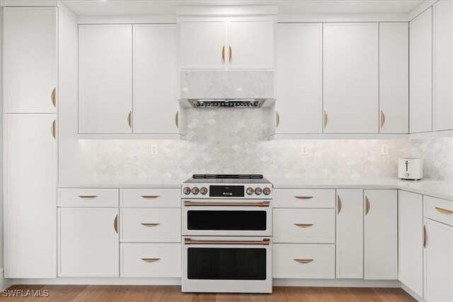 4951 Bonita Bay Blvd Unit 2205, Bonita Springs, FL 34134 - kitchen featuring double oven range, light countertops, white cabinets, tasteful backsplash, and exhaust hood