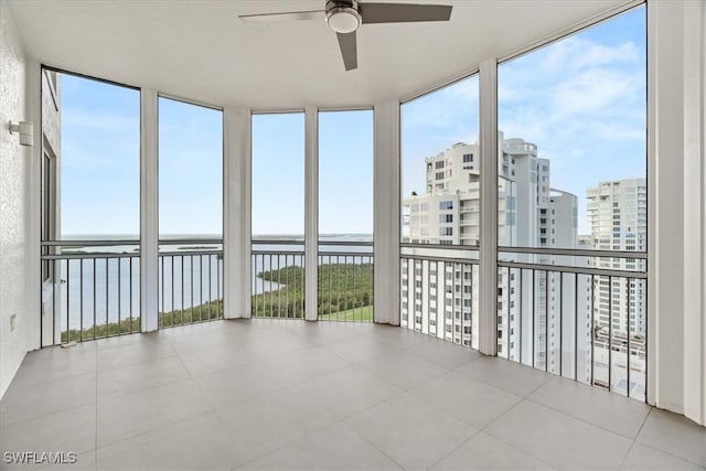 unfurnished sunroom with ceiling fan, a healthy amount of sunlight, and a water view