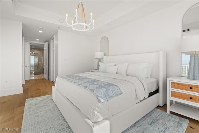 bedroom with a raised ceiling, light hardwood / wood-style floors, an inviting chandelier, and crown molding