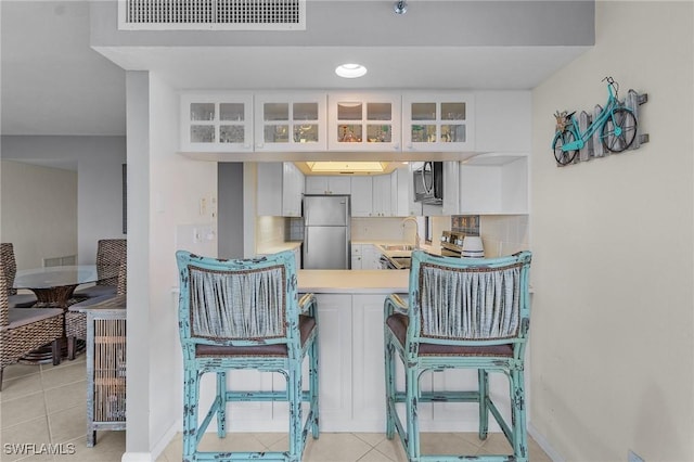 dining area with light tile patterned floors, visible vents, and baseboards