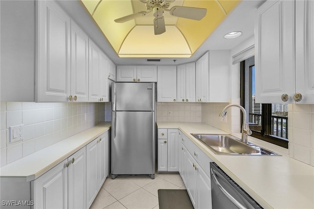 kitchen with light tile patterned floors, a sink, stainless steel appliances, white cabinets, and a raised ceiling