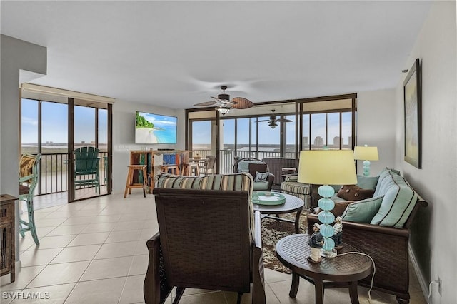 living area featuring light tile patterned floors, expansive windows, and ceiling fan